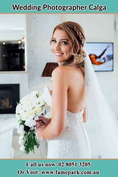 The Bride holding a bouquet of flowers smiles in front of the camera Calga