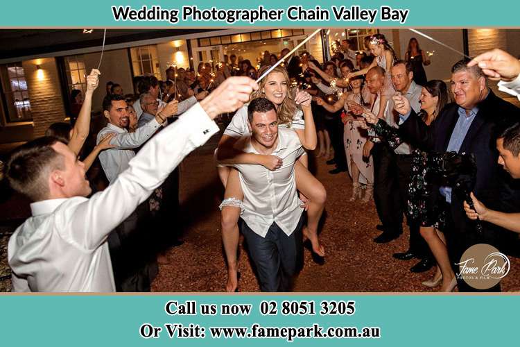 Photo of the Groom Carrying her Bride as their loved ones cheered on Chain Valley Bay