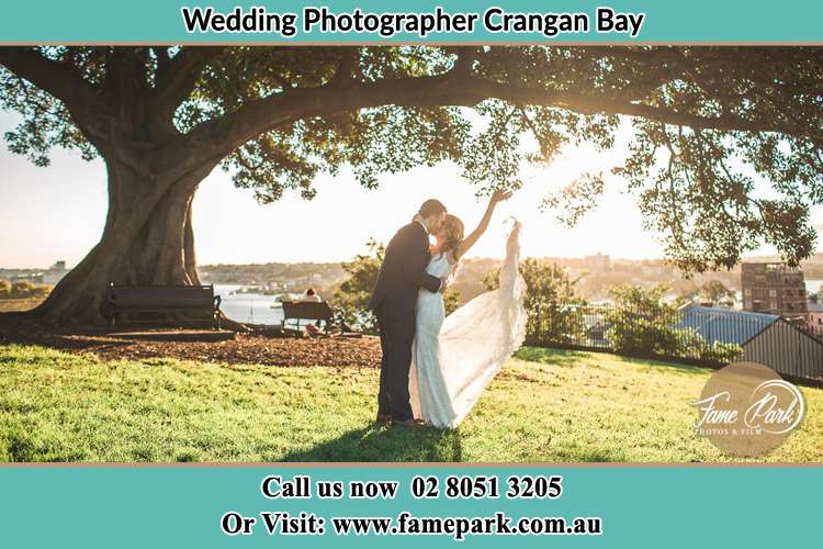 Photo of the new couple kissing under a big tree Crangan Bay