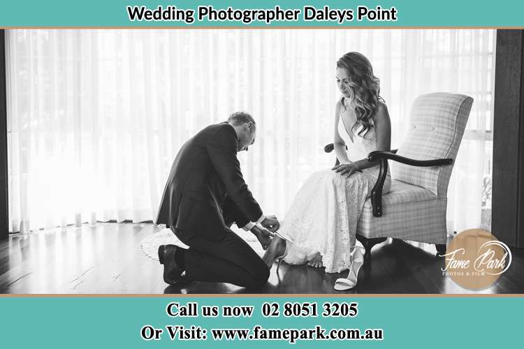 The Bride is being helped by the Groom trying to put on her shoes Daleys Point NSW 2257