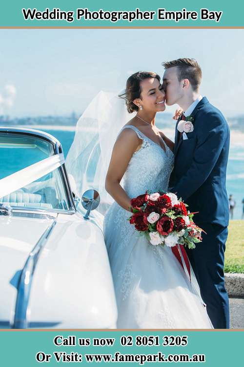 Photo of the Bride kiss by the Groom besides the bridal car Empire Bay NSW 2257