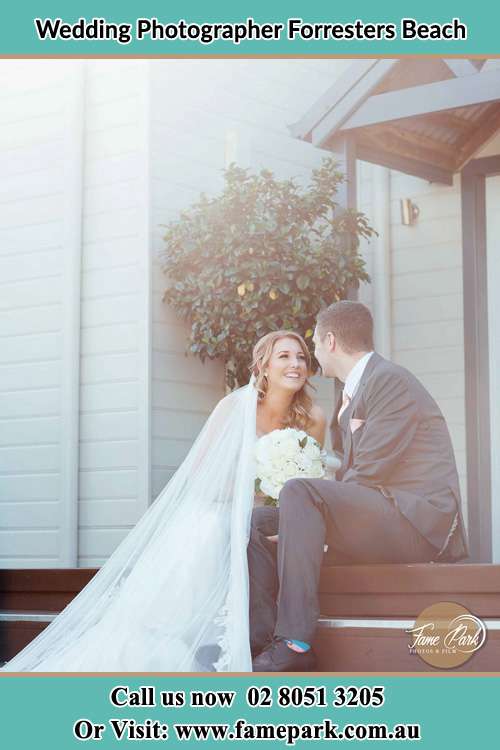 Photo of the Bride and the Groom looking each other while sitting at the staircase Forresters Beach NSW 2260