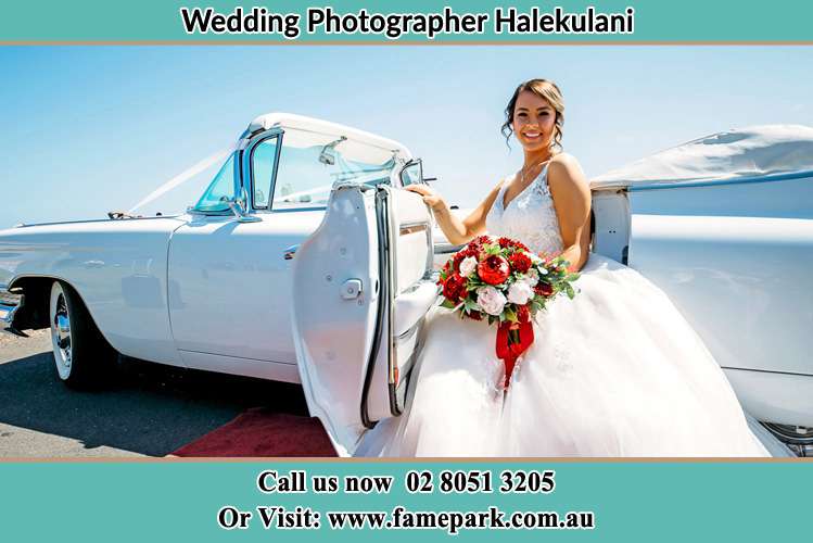 The Bride holding bouquet of flowers besides her bridal car Halekulani