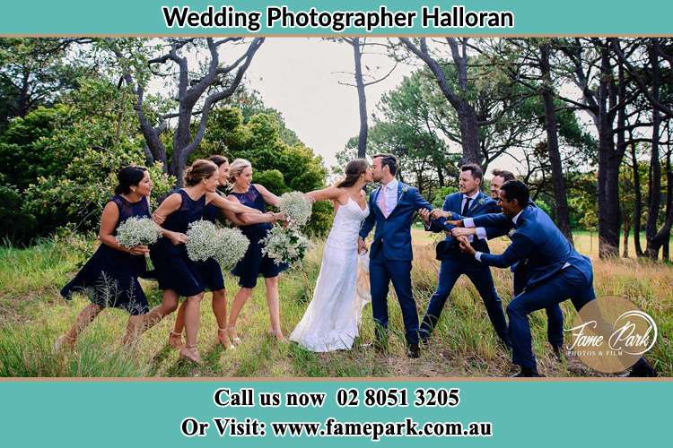 Photo of the Bride and the Groom kissing while teasing by the entourage Halloran NSW 2259