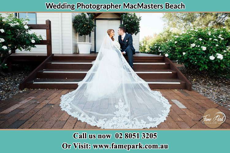 Photo of the Bride and the Groom looking each other while sitting at the staircase MacMasters Beach NSW 2251