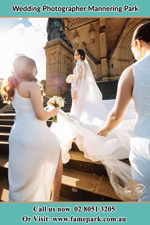 Photo of the Bride smiling to the bridesmaid holding the tail of her wedding gown at the front of the church Mannering Park NSW 2250